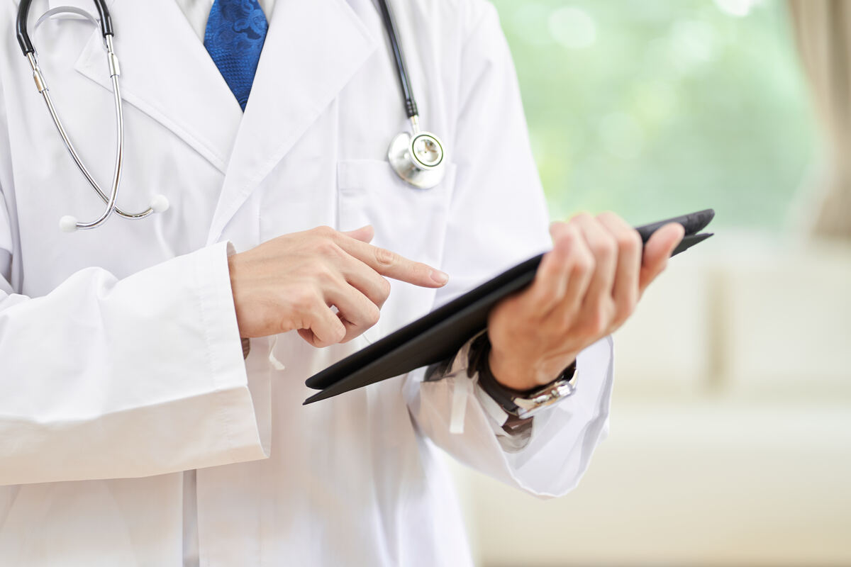 Mãos de um médico do sexo masculino com um prontuário eletrônico