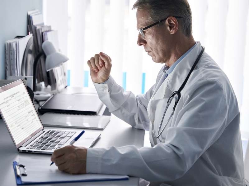 Médico usando computador no consultório.