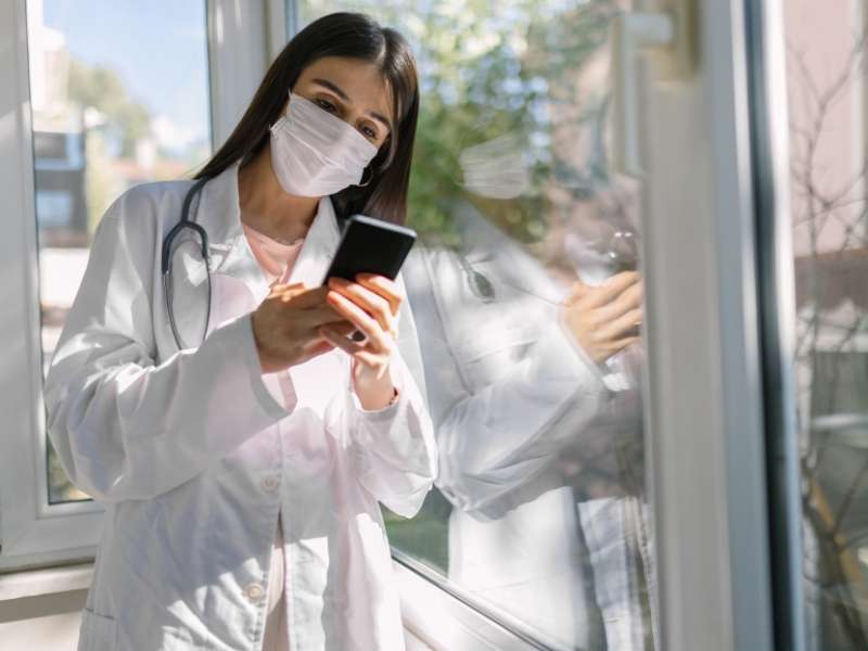Médica usando celular para comprar móveis.