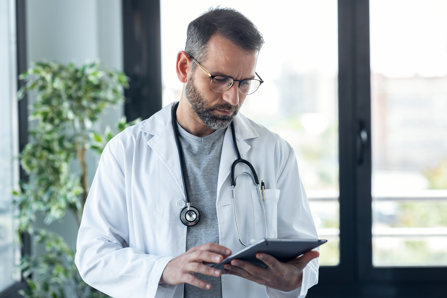 médico masculino com óculos, revisando relatórios médicos em uma consulta médica.